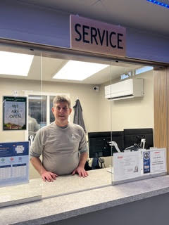 A person stands behind a service counter in an office environment.