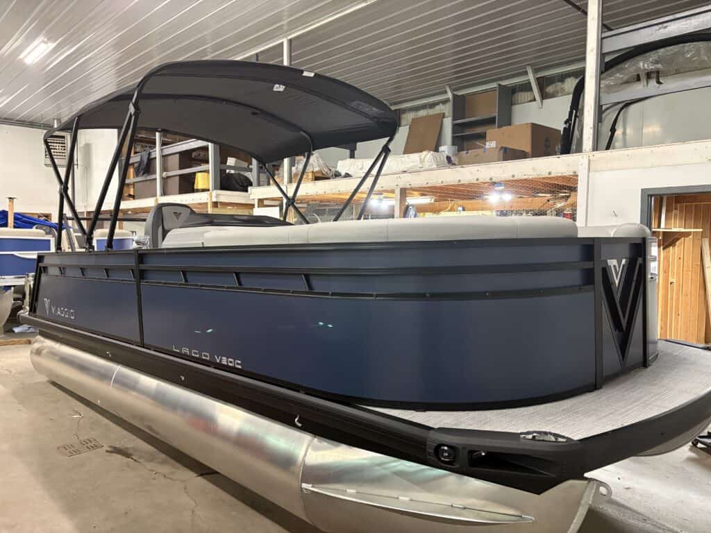 Lago's V20C blue pontoon boat, featuring a sleek cover, is perfectly nestled indoors.